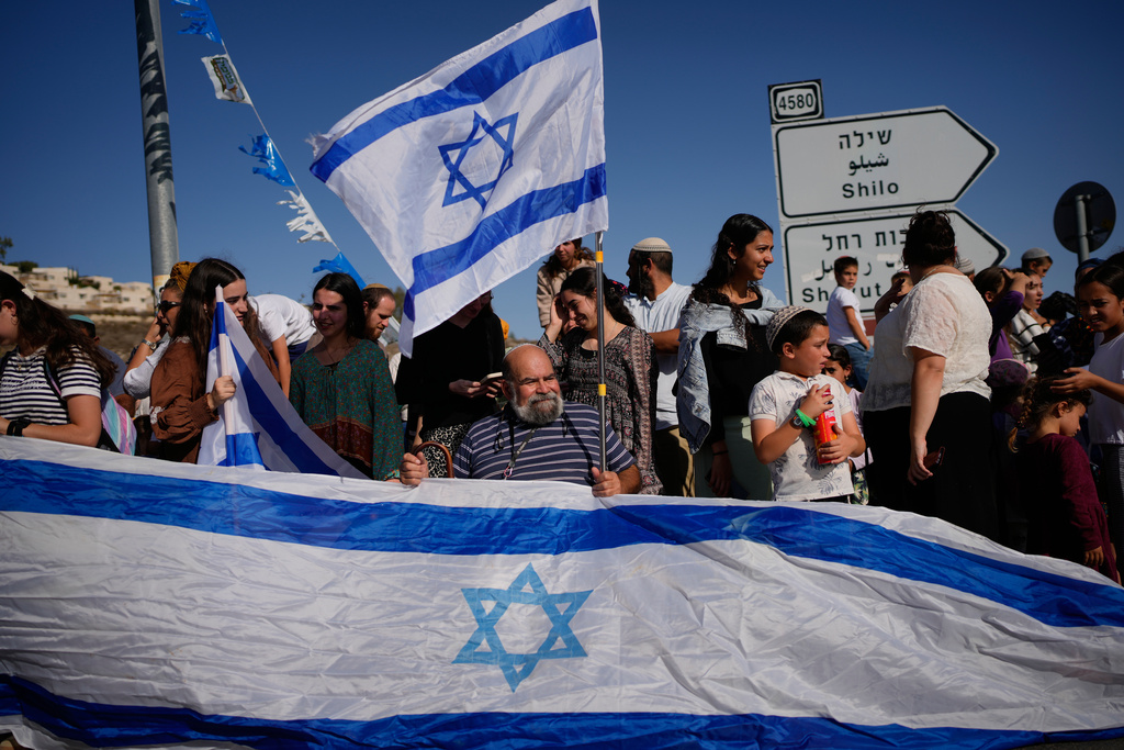 People gather to welcome freed Israeli hostage, Avinatan Or, who was recently released from Hamas captivity in Gaza, as he return from the hospital to his home at the West Bank settlement of Shilo, Tuesday, Oct. 21, 2025. (AP Photo/Ohad Zwigenberg)
