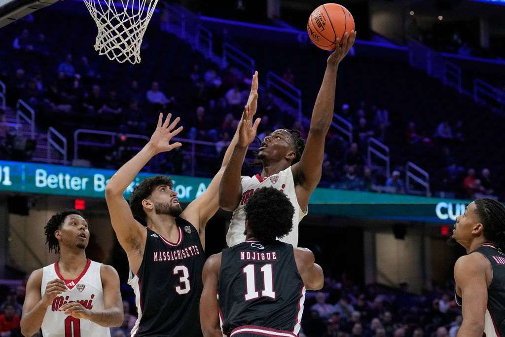 Miami (Ohio) forward Antwone Woolfolk shoots over Massachusetts' Leonardo Bettiol (3) and Jayden Ndjigue (11) in the first half of an NCAA college basketball game in the quarterfinals of the Mid-American Conference tournament, Thursday, March 12, 2026, in Cleveland. (AP Photo/Sue Ogrocki)