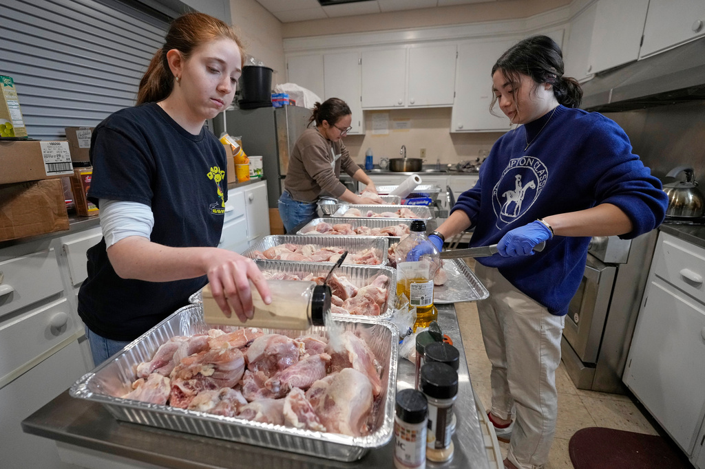 Colby College students Hannah Rothenberg, left, Ava Shapiro, right, and Becca Hoffman, prepare chicken for a passover meal Monday, March 30, 2026, at the Beth Israel Synagogue in Waterville, Maine. (AP Photo/Robert F. Bukaty)