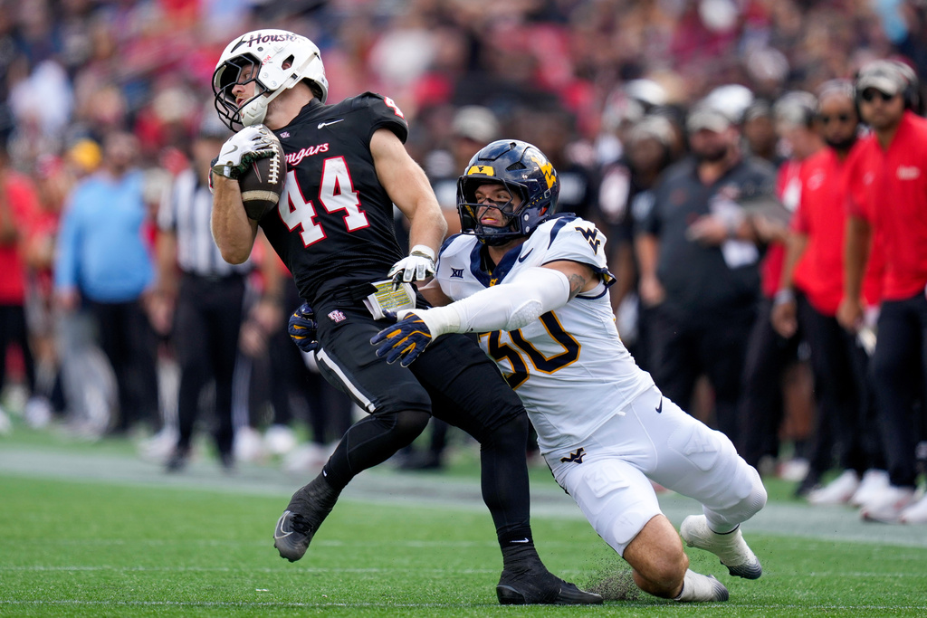 Houston running back Dean Connors (44) avoids the tackle of West Virginia linebacker Chase Wilson during the first half of an NCAA college football game Saturday, Nov. 1, 2025, in Houston. (AP Photo/Eric Christian Smith)