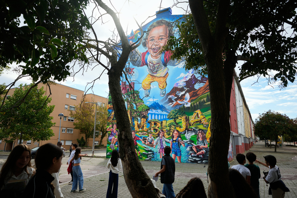 School children on a tour look at a mural by artist Pedro das Neves, inspired by the United Nations Sustainable Development Goal 6, Clean Water and Sanitation, at the housing project Zambujal in Amadora, on the outskirts of the Portuguese capital Lisbon, Monday, Nov. 3, 2025. (AP Photo/Armando Franca)