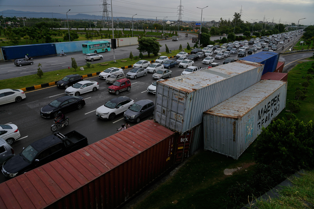 Vehicles drive past shipping containers placed by authorities along side on a highway for seal off an area ahead of a plan protest march by the supporters of imprisoned former Prime Minister Imran Khan demanding his release, in Islamabad, Pakistan, Monday, Sept. 28, 2026. (AP Photo/Anjum Naveed)