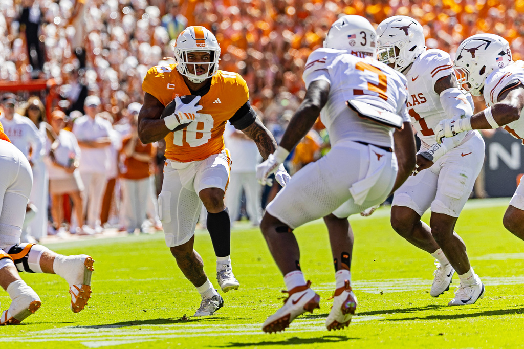 Tennessee running back DeSean Bishop (18) runs for yardage as he avoids Texas linebacker Rasheem Biles (3) and defensive end Colin Simmons (1) during the first half of an NCAA college football game, Saturday, Sept. 26, 2026, in Knoxville, Tenn. (AP Photo/Wade Payne)