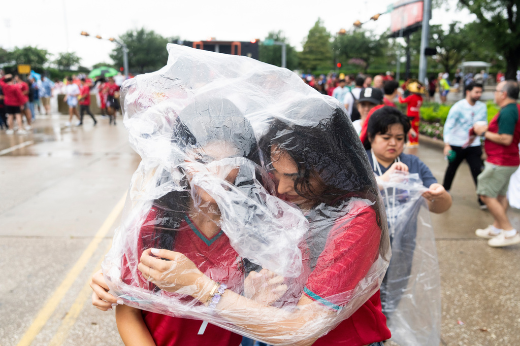 Portugal fans share a single poncho as rain falls on fans while waiting to enter Houston Stadium before a FIFA World Cup between Portugal and DR Congo in Houston, Wednesday, June 17, 2026. (Jason Fochtman/Houston Chronicle via AP)
