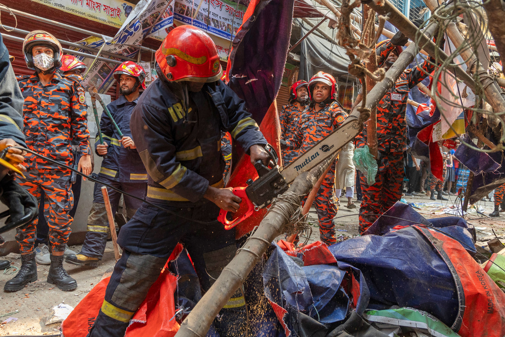 Rescue and fire officials cut building railings falling on the street to make way after an earthquake in Dhaka, Bangladesh, Friday, Nov. 21, 2025. (AP Photo/Abdul Goni)