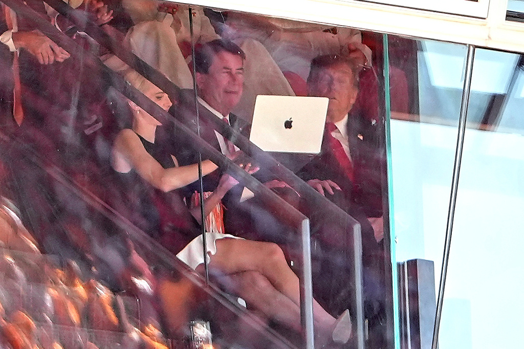 White House aide Natalie Harp, left, holds up a laptop for President Donald Trump, right, and Sen. Bill Hagerty, R-Tenn., center, during an NCAA college football game between Tennessee and Texas at Neyland Stadium, Saturday, Sept. 26, 2026, in Knoxville, Tenn. (AP Photo/Julia Demaree Nikhinson)