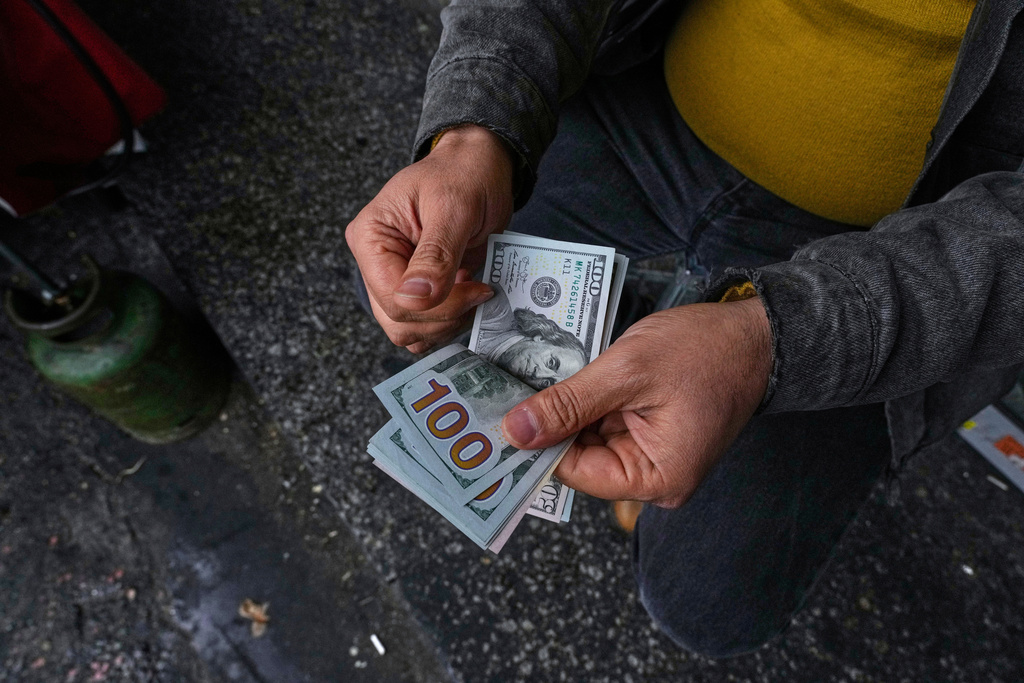 FILE—A street currency exchanger poses for a photo without showing his face as he counts U.S. dollars at Ferdowsi square, Tehran's go-to venue for foreign currency exchange, in downtown Tehran, Iran, April 5, 2025. (AP Photo/Vahid Salemi, File)