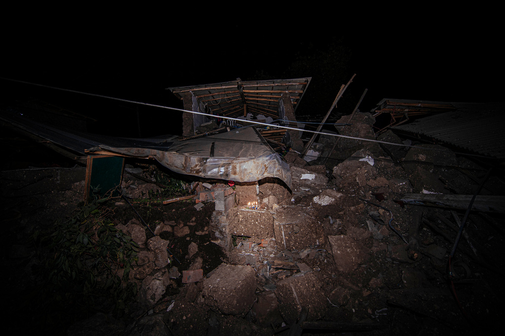 Lit candles stand amid the rubble of a house that collapsed after an earthquake struck Pumpuya, Peru, Sunday, July 19, 2026.( AP Photo/Javier Ninanya)