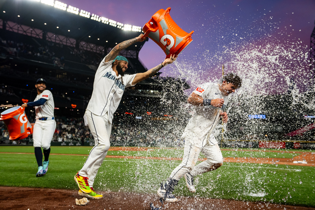 Seattle Mariners' J.P. Crawford, middle, and Julio Rodriguez, left, douse Cole Young with water after a baseball game against the New York Mets, Monday, June 1, 2026, in Seattle. (AP Photo/Stephen Brashear)
