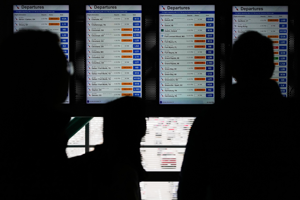 Travelers check their flight times on a information screen at the O'Hare International Airport in Chicago, Sunday, Nov. 30, 2025. (AP Photo/Nam Y. Huh)