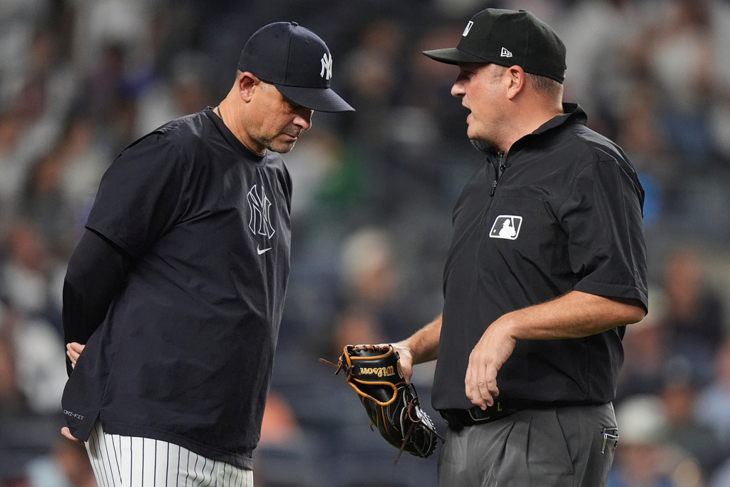 New York Yankees manager Aaron Boone, left, speaks with umpire Dan Bellino who's holding a glove taken from Chicago White Sox pitcher Tyler Gilbert during the fifth inning of a baseball game Thursday, Sept. 25, 2025, in New York. (AP Photo/Frank Franklin II)