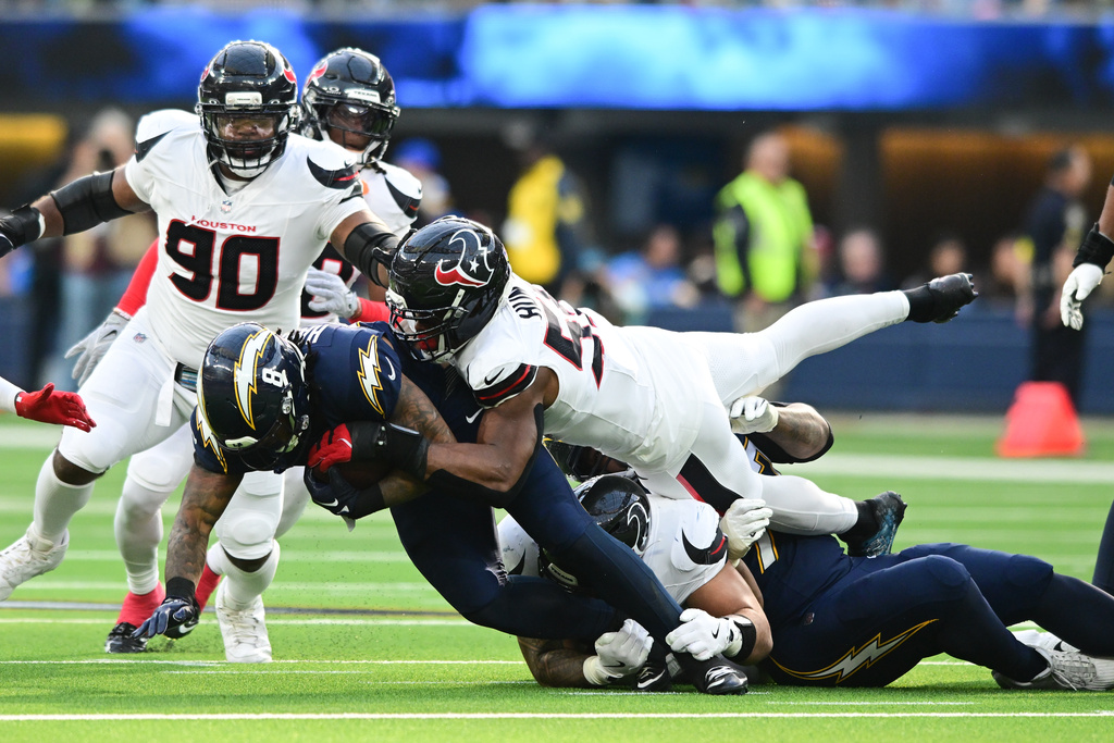 Los Angeles Chargers running back Omarion Hampton (8) is stopped by Houston Texans defensive end Danielle Hunter (55) during the first half of an NFL football game Saturday, Dec. 27, 2025, in Inglewood, Calif. (AP Photo/Wally Skalij)