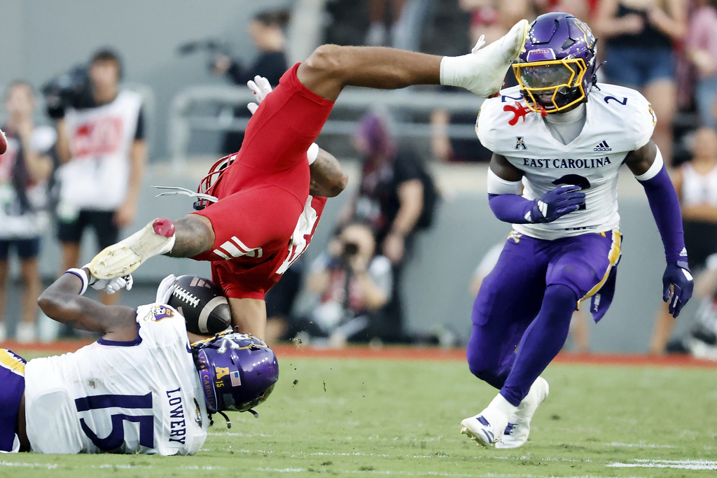 North Carolina State's Teddy Hoffmann, top left, is upended by East Carolina's Jordy Lowery (15) with East Carolina's Ja'Marley Riddle (2) nearby during the first half of an NCAA college football game in Raleigh, N.C., Thursday, Aug. 28, 2025. (AP Photo/Karl DeBlaker)