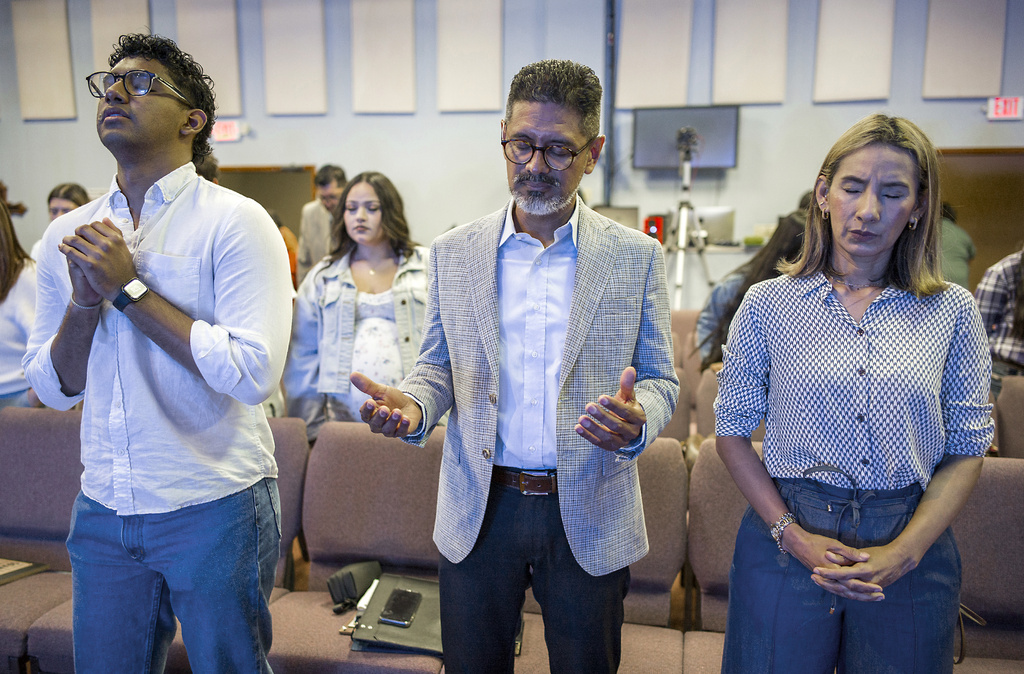 Jos&eacute; Luis Orozco, a pastor from Nicaragua, prays with his son, Josias, 17, left, and wife, Ruth, before speaking to members of the Oasis Church, in Taylor, Texas, June 15, 2025. (AP Photo/Rodolfo Gonzalez)