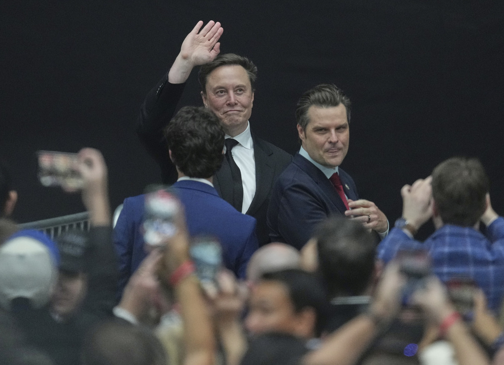 Elon Musk, left, waves to supporters alongside former Rep. Matt Gaetz during a memorial for Charlie Kirk, Sunday, Sept. 21, 2025, at State Farm Stadium in Glendale, Ariz. (AP Photo/Ross D. Franklin)