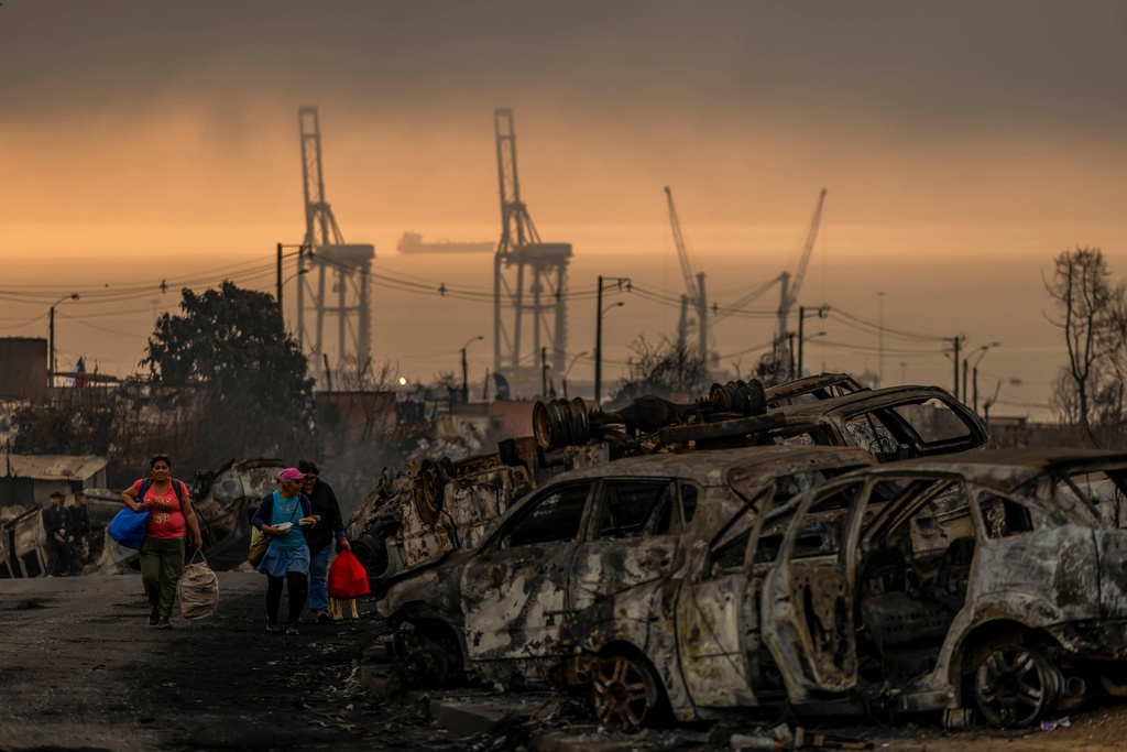 People transport food to victims of wildfires in Lirquen, Chile, Tuesday, Jan. 20, 2026. (AP Photo/Javier Torres)