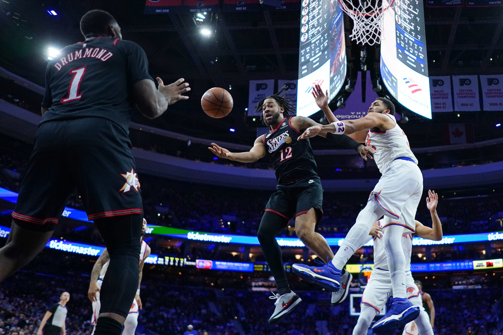 Philadelphia 76ers' Trendon Watford (12) passes Andre Drummond (1) past New York Knicks' Karl-Anthony Towns, right, during the first half of an NBA basketball game Wednesday, Feb. 11, 2026, in Philadelphia. (AP Photo/Matt Rourke)