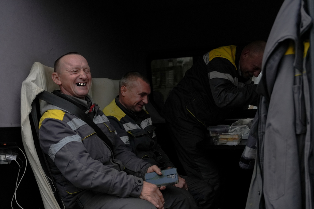 DTEK workers Roman Gerasymchuk, Andriy Korniychuk and Igor Kryvenko laugh while sitting down in their brigade's van before a long drive back to their base following scheduled repair work on an energy substation, Friday, Oct. 24, 2025, in Kyiv region, Ukraine. (AP Photo/Julia Demaree Nikhinson)