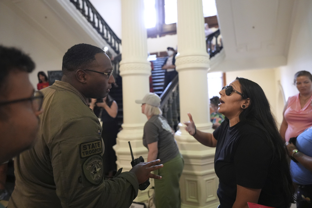 A Texas state trooper engages with a protester over noise volume outside of the House Chamber where Democratic Texas Rep. Nicole Collier refuses to leave due to a required law enforcement escort, Tuesday, Aug. 19, 2025, in Austin, Texas. (AP Photo/Eric Gay)