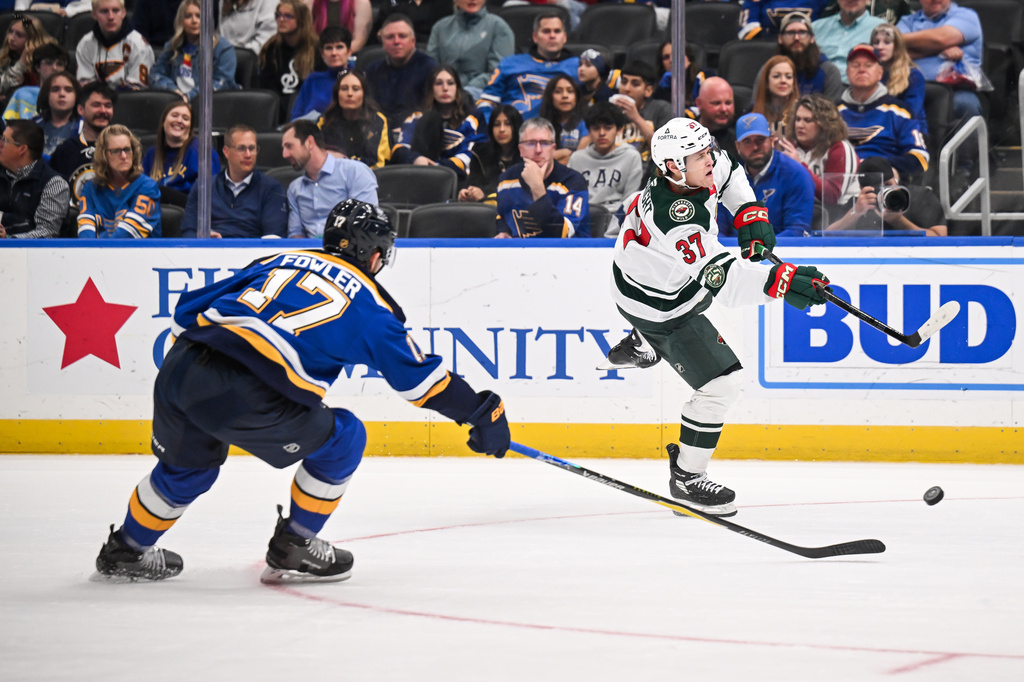 Minnesota Wild's Hunter Haight (37) shoots while St. Louis Blues' Cam Fowler (17) defends during the third period of an NHL hockey game Monday, April 13, 2026, in St. Louis. (AP Photo/Connor Hamilton)