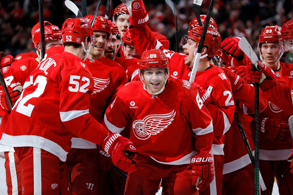 Detroit Red Wings right wing Patrick Kane (88) is surrounded by teammates after recording his 1,375th point to pass Mike Modano and break the NHL record for points by a player born in the United States, during the second period of an NHL hockey game Thursday, Jan. 29, 2026, in Detroit. (AP Photo/Duane Burleson)