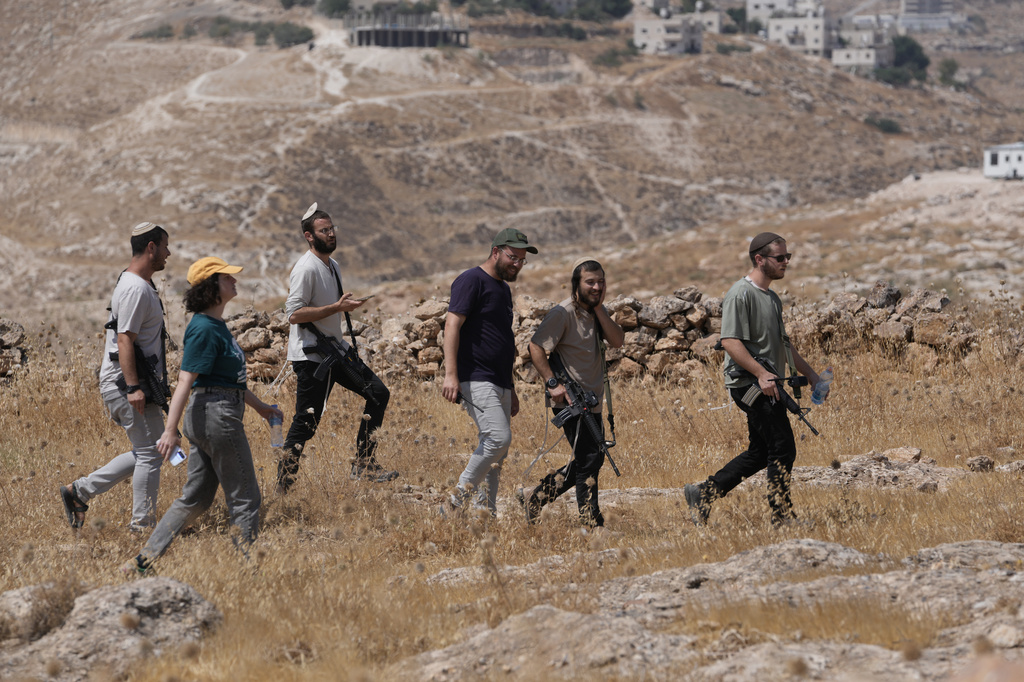 Israeli settlers gather from a nearby outpost after Israeli and foreign peace activists took down a metal structure in the shape of a Star of David from atop a Palestinian structure during a protest in support of local landowners whose property is threatened with seizure by settlers, on the outskirts of the West Bank city of Beit Sahour, Friday, Aug. 14, 2026. (AP Photo/Mahmoud Illean)