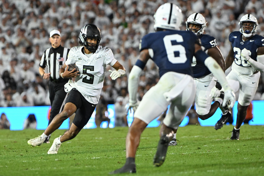 Oregon quarterback Dante Moore (5) looks to elude Penn State safety Zakee Wheatley (6) during the first quarter of an NCAA college football game, Saturday, Sept. 27, 2025, in State College, Pa. (AP Photo/Barry Reeger)