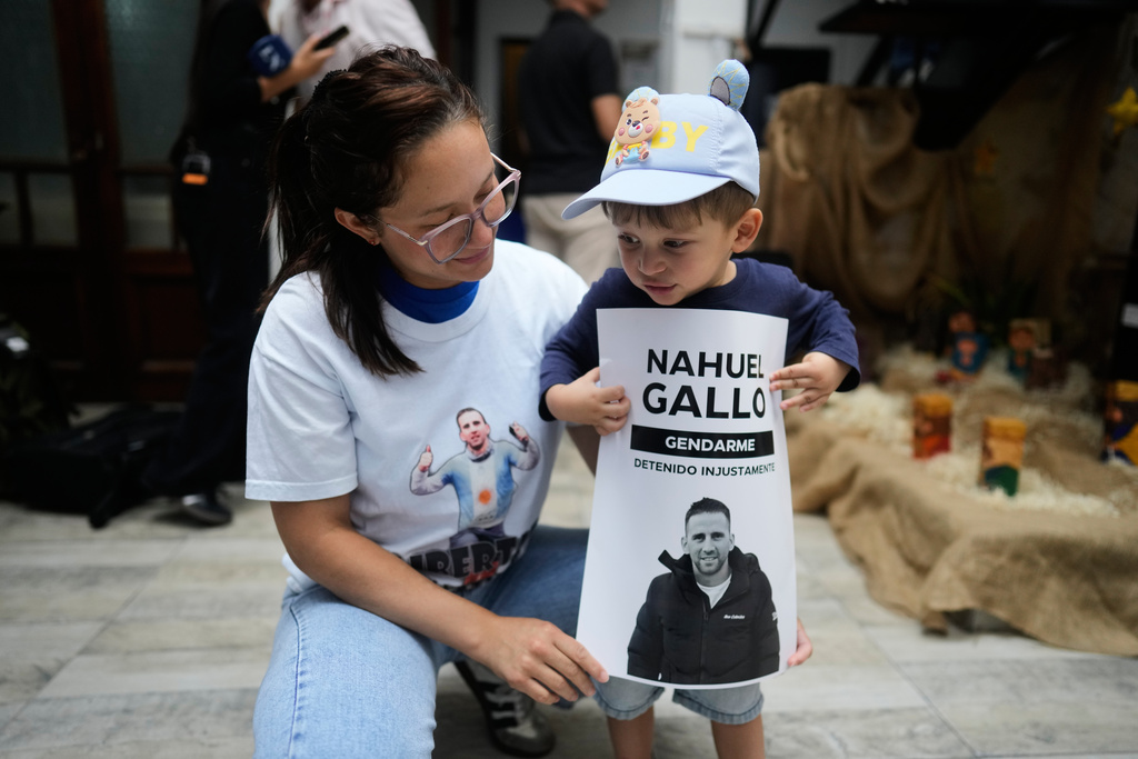 Maria Alexandra Gomez, girlfriend of detained Argentine officer Nahuel Agustin Gallo, stands with their son Victor during a gathering of friends and relatives of people detained in Venezuela at a community center where they wait for news of their loved ones' release in Buenos Aires, Argentina, Thursday, Jan. 8, 2026, after Venezuelan authorities said the they would release Venezuelan and foreign prisoners. (AP Photo/Natacha Pisarenko)