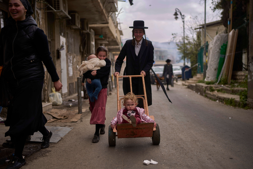 FILE - A child is transported on a dolly in the Orthodox neighborhood of Mea Shearim in Jerusalem during final preparations for the Passover holiday, April 11, 2025. (AP Photo/Ohad Zwigenberg, File)