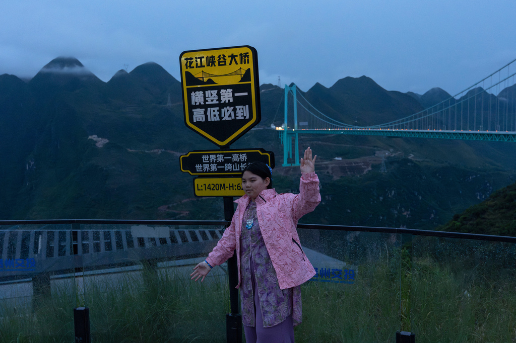 A tourist poses near a sign promoting the Huajiang Grand Canyon Bridge as having the world's highest and longest dimensions in Anshun in southwestern China's Guizhou province on Friday, May 29, 2026. (AP Photo/Ng Han Guan)