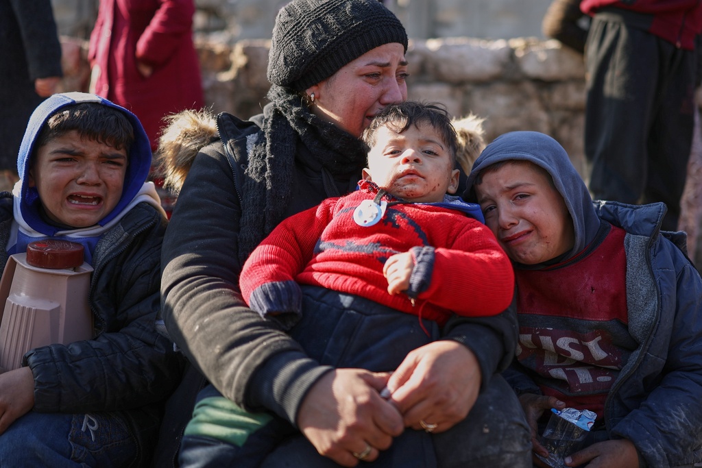 A woman and her children react with distress as civilians evacuate an area of the Sheikh Maqsoud neighborhood, where clashes between government forces and Kurdish fighters have been taking place in the northern city of Aleppo, Syria, Saturday, Jan. 10, 2026. (AP Photo/Ghaith Alsayed)