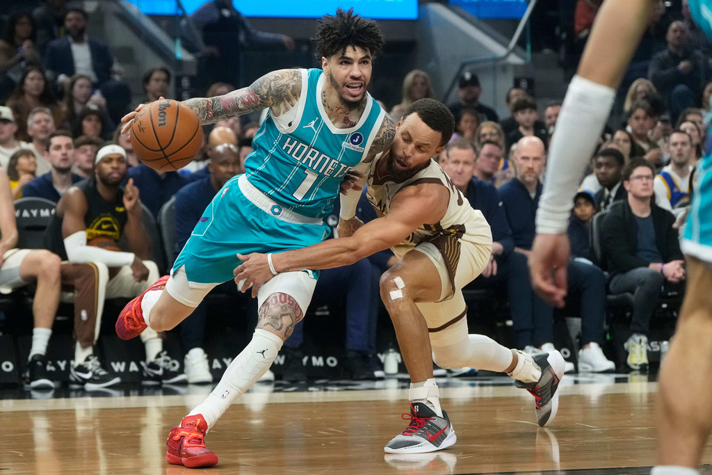 Charlotte Hornets guard LaMelo Ball (1) drives to the basket against Golden State Warriors guard Stephen Curry during the first half of an NBA basketball game in San Francisco, Saturday, Jan. 17, 2026. (AP Photo/Jeff Chiu)