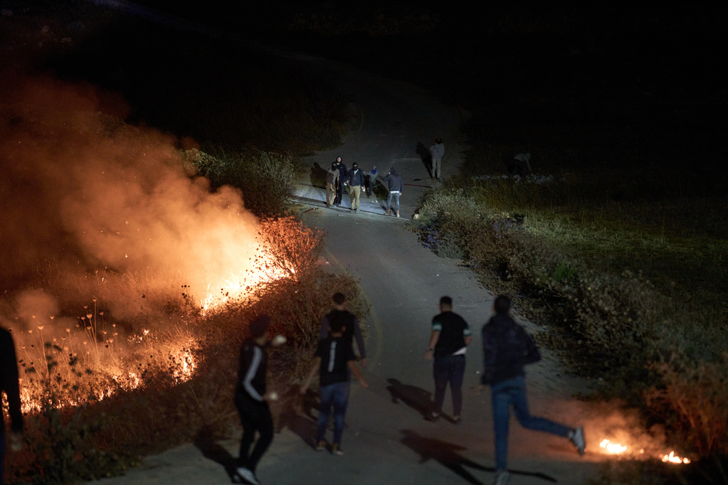 Israeli settlers, top, and Palestinians clash as brush burns along a roadside after Palestinians set it ablaze to prevent the settlers from approaching the West Bank village of Sinjil, Friday, July 17, 2026. (AP Photo/Leo Correa)