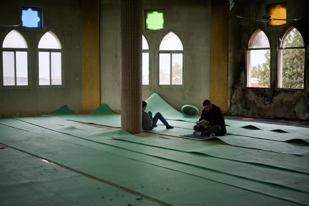 A Palestinian man reads the Quran before Friday prayers at a mosque that was torched and defaced by Israeli settlers in the West Bank village of Deir Istiya, Friday, Nov. 14, 2025. (AP Photo/Leo Correa)