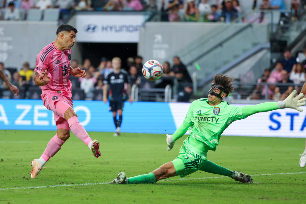 Inter Miami forward Luis Suárez, left, shoots as San Diego FC goalkeeper CJ Dos Santos, right, defends during the first half of an MLS soccer game, Sunday, Sept. 20, 2026, in Miami. (AP Photo/David Santiago)