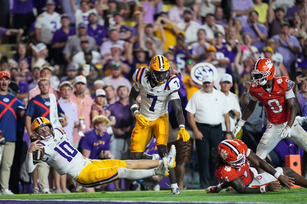 LSU quarterback Sam Leavitt (10) carries for a touchdown against Clemson defensive end London Merritt (14) and cornerback Corian Gipson (8) in the first half of an NCAA college football game, Saturday, Sept. 5, 2026 in Baton Rouge, La. (AP Photo/Gerald Herbert)
