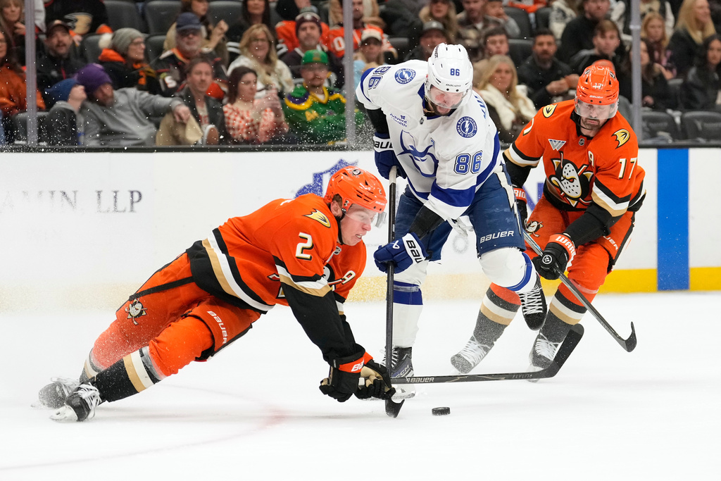 Anaheim Ducks defenseman Jackson Lacombe, left, falls as he tries to pass the puck while under pressure from Tampa Bay Lightning right wing Nikita Kucherov, center as left wing Alex Killorn skates behind during the second period of an NHL hockey game Wednesday, Dec. 31, 2025, in Anaheim, Calif. (AP Photo/Mark J. Terrill)