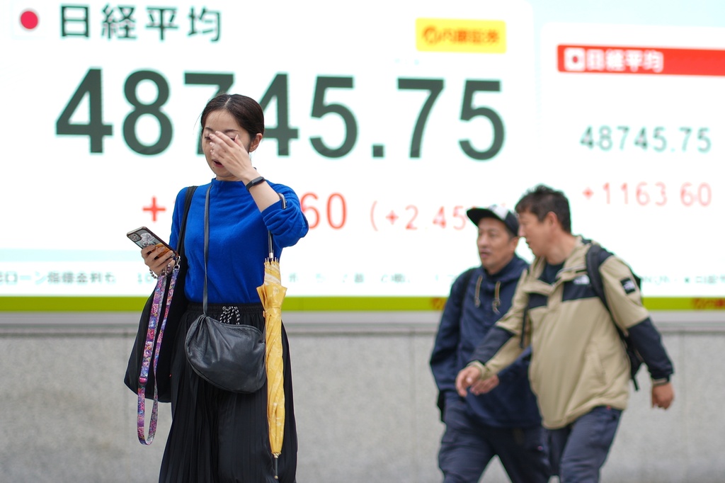 People walk in front of an electronic stock board showing Japan's Nikkei index at a securities firm Monday, Oct. 20, 2025, in Tokyo. (AP Photo/Eugene Hoshiko)