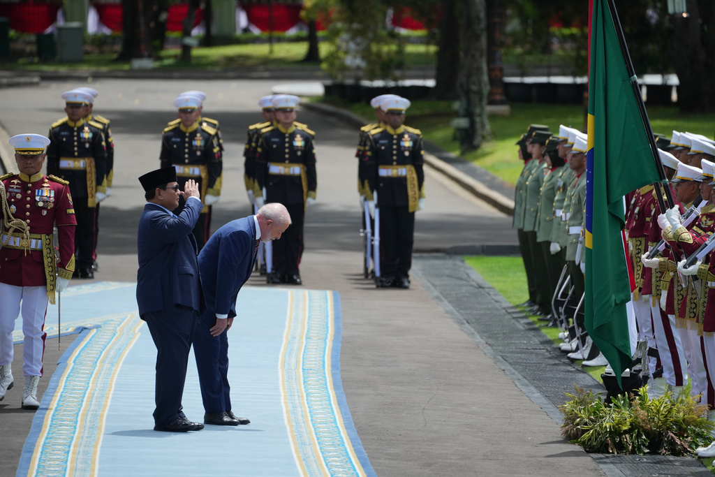 Indonesian President Prabowo Subianto, left, and Brazil's President Luiz Inacio Lula da Silva salute their national flags as they inspect honor guards during a welcoming ceremony prior to their meeting at Merdeka Palace in Jakarta, Indonesia, Thursday, Oct. 23, 2025. (AP Photo/Achmad Ibrahim)