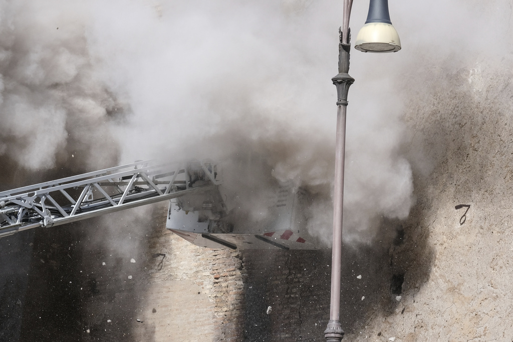 A cloud of debris from a second collapse is seen surrounding firefighters who were trying to rescue a worker after a medieval tower near the Roman Forum partially collapsed during renovation work, in Rome, Monday Nov. 3 2025. (Mauro Scrobogna/LaPresse via AP)