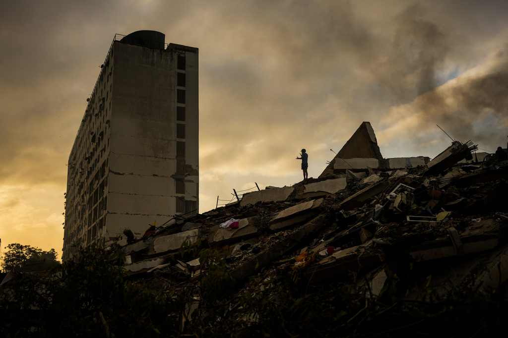 A man stands atop a mountain of rubble three days after twin earthquakes struck, in La Guaira, Venezuela, Saturday, June 27, 2026. (AP Photo/Matias Delacroix)