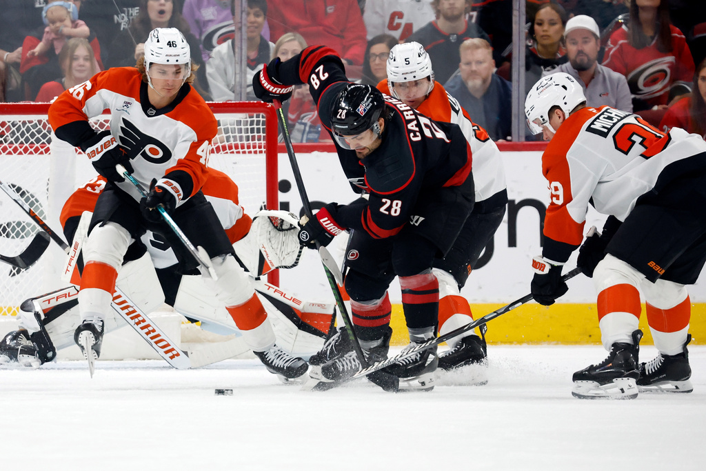 Carolina Hurricanes' William Carrier (28) controls the puck between Philadelphia Flyers defenders during the first period of an NHL hockey game in Raleigh, N.C., Saturday, Oct. 11, 2025. (AP Photo/Karl DeBlaker)
