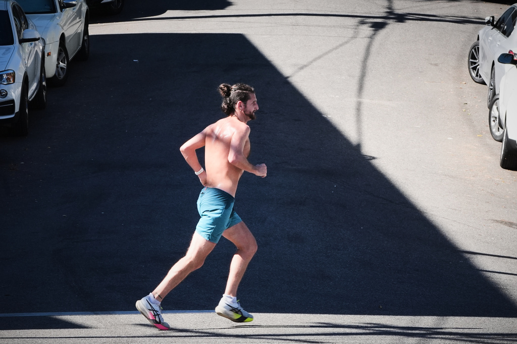 A jogger crosses a street on an unseasonably hot day Tuesday, Oct. 28, 2025, in Los Angeles. (AP Photo/Damian Dovarganes)