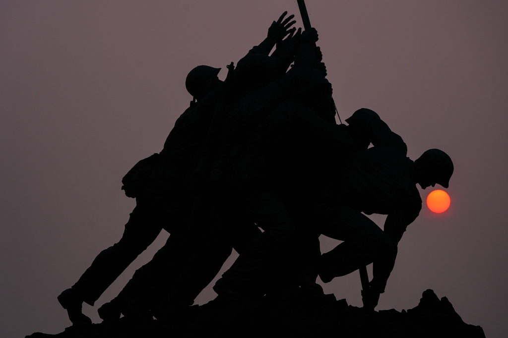 The sun is obscured by wildfire smoke as it rises behind the Marine Corps War Memorial, Friday, July 17, 2026, in Arlington, Va. (AP Photo/Julia Demaree Nikhinson)