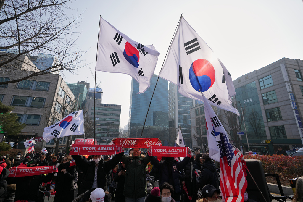 Supporters of former South Korean President Yoon Suk Yeol hold signs and flags outside Seoul Central District Court, in Seoul, South Korea, Friday, Jan. 16, 2026. (AP Photo/Lee Jin-man)