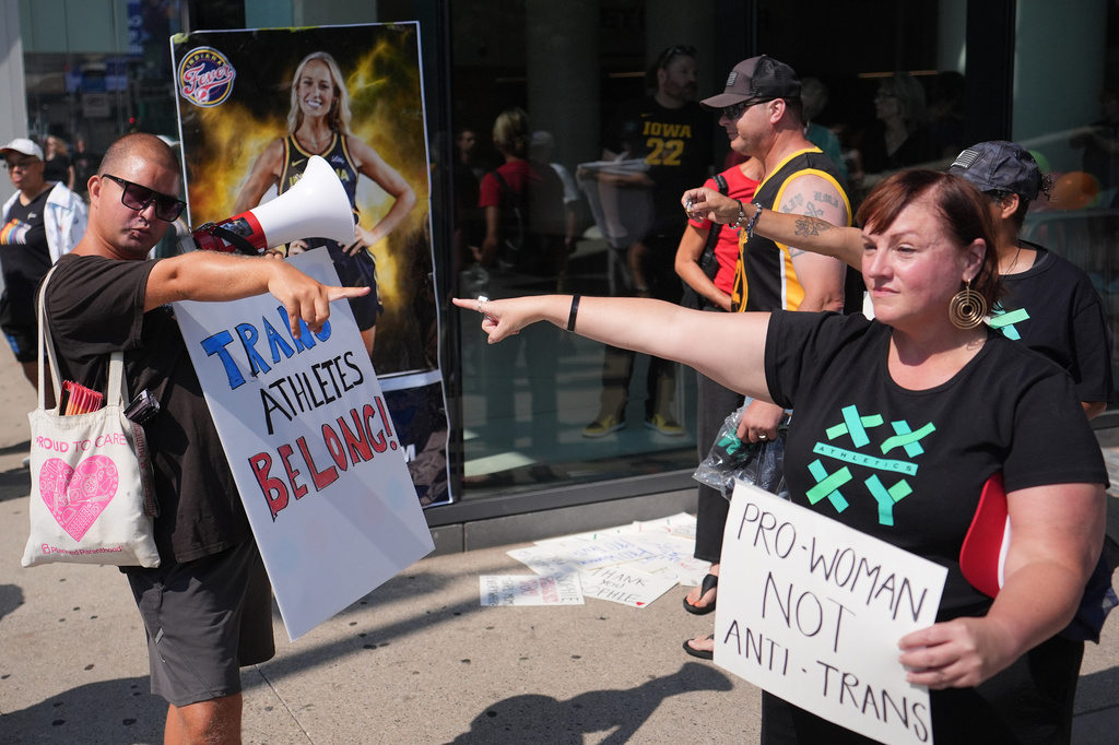 FILE - People hold signs and point after comments on transgender athletes made by Indiana Fever guard Sophie Cunningham, before a WNBA basketball game between the Minnesota Lynx and Indiana Fever, Aug. 2, 2026, in Minneapolis. (AP Photo/Abbie Parr, File)