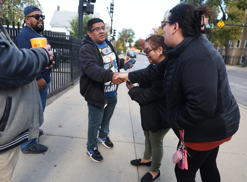Baltazar Enriquez, president of the Little Village Community Council, shakes hands with a local resident while patrolling for U.S. Immigration and Customs Enforcement (ICE) agents in Chicago's Little Village neighborhood, Wednesday, Oct. 29, 2025. (AP Photo/Talia Sprague)