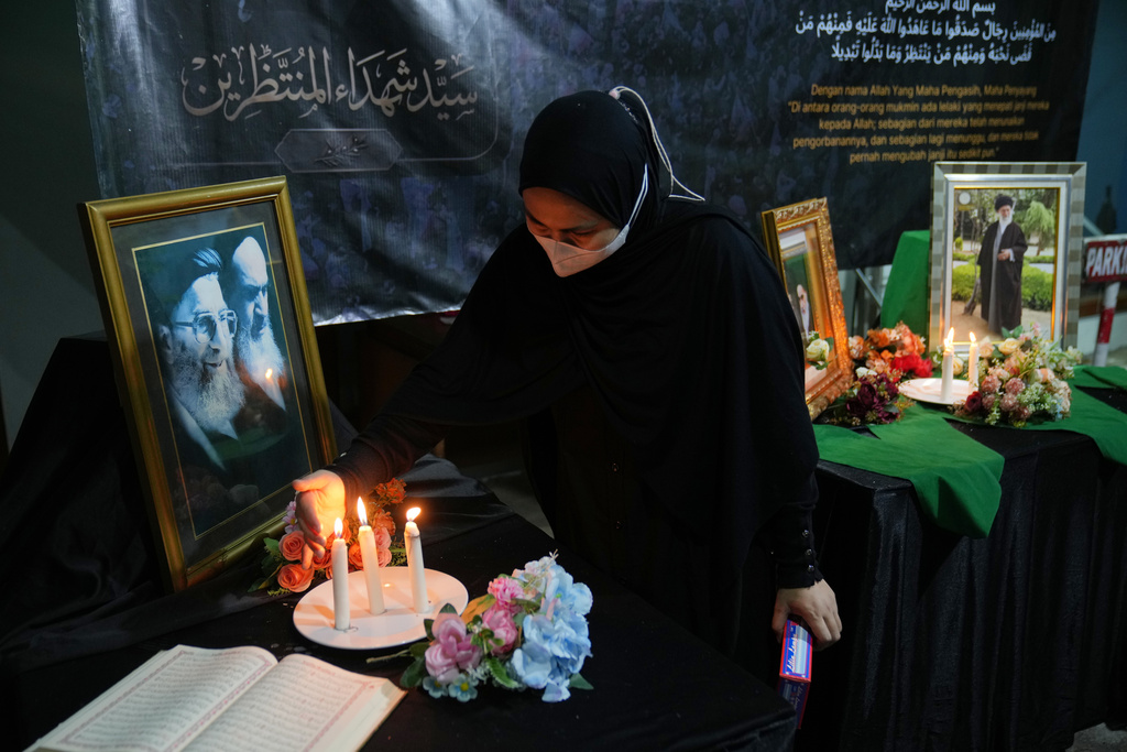 A woman lights candles near the portraits of the late Iranian Supreme Leader Ayatollah Ali Khamenei during a prayer in Jakarta, Indonesia, Monday, March 2, 2026. (AP Photo/Dita Alangkara)