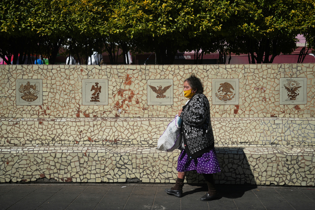 People sit on benches in Plaza del Aguilita, where the evolution of the Mexican coat of arms is showcased, Mexico City, Thursday, Nov. 13, 2025. (AP Photo/Claudia Rosel)