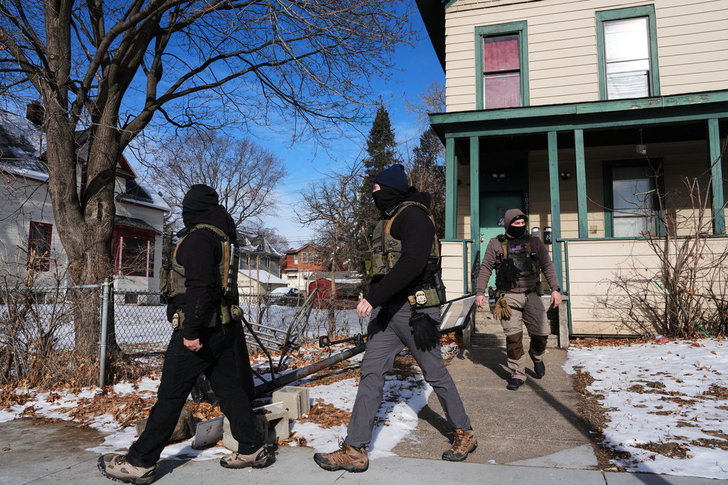 Federal immigration officers walk away after knocking on a door Monday, Jan. 26, 2026, in St. Paul, Minn. (AP Photo/Adam Gray)